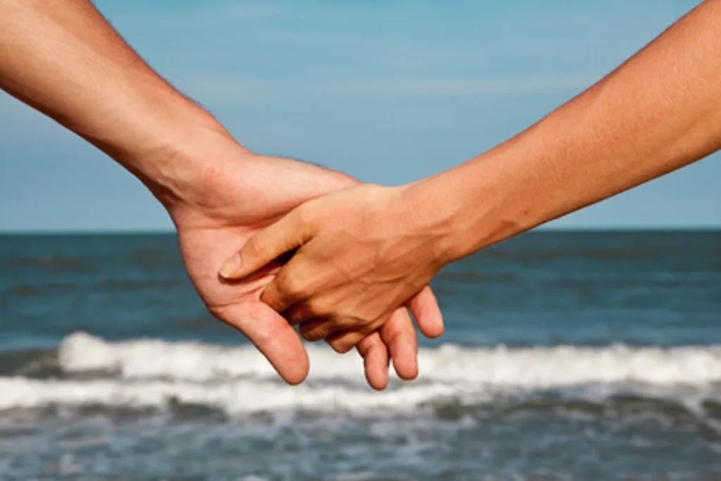 intimately holding hands at the ocean